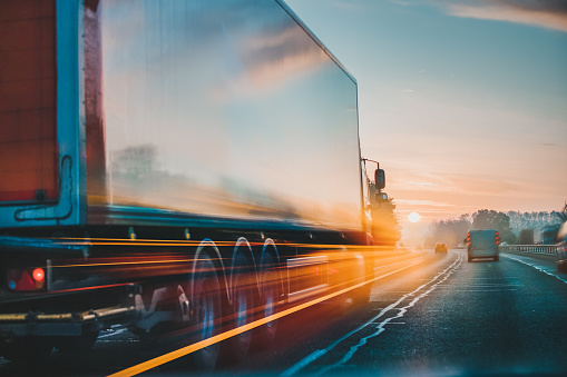 A semi-truck traveling fast down a highway