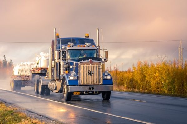 blue flatbed semi-truck going down a wet Florida roadway