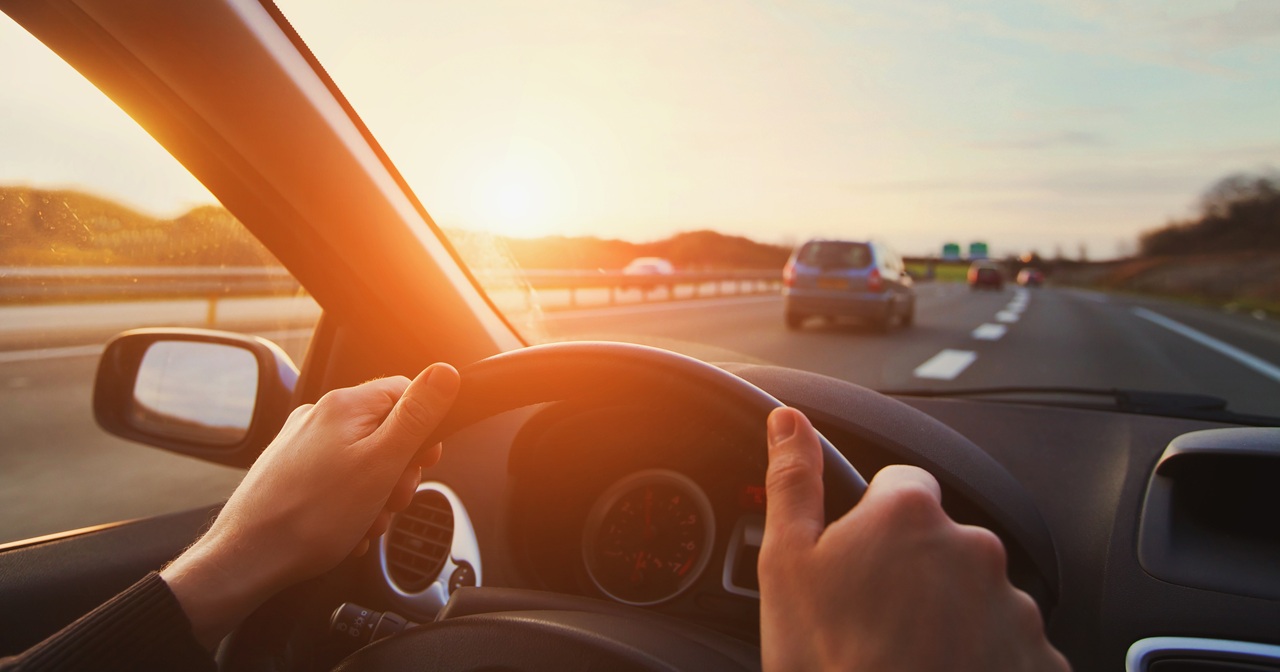 A driver's hands grip the steering wheel of a borrowed car on a highway at sunset, illustrating Florida's dangerous instrumentality doctrine, which can hold a vehicle owner liable for crashes caused by someone they allowed to drive.